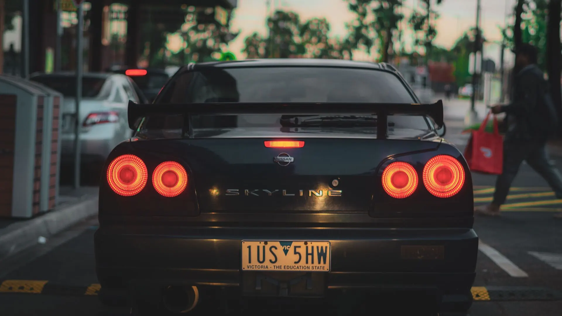 The rear of a car with its tail lights lit on a city street
